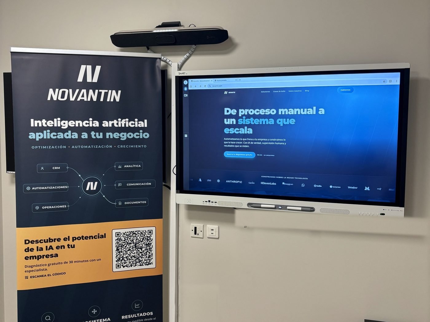 Sala de reuniones de Novantin con el rollup de la empresa y la pantalla mostrando novantin.com